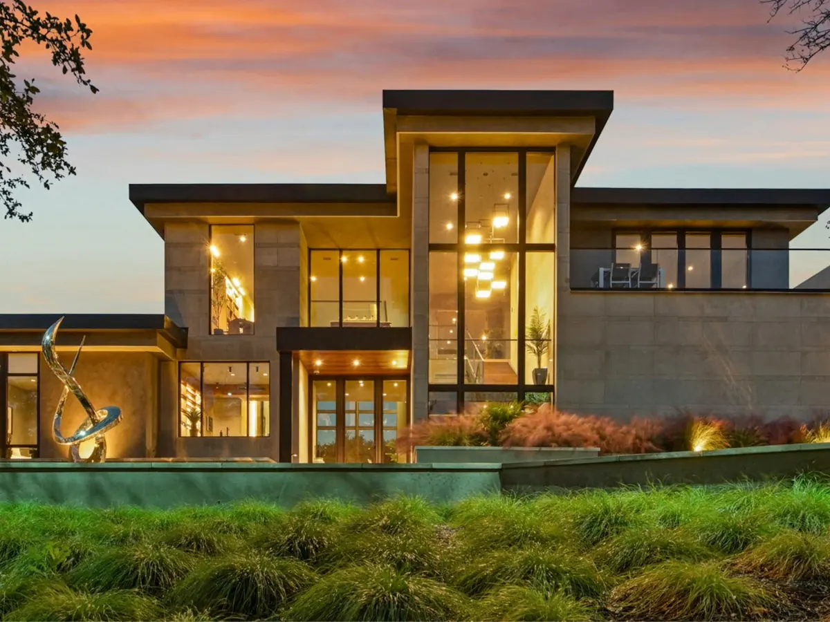 Contemporary luxury villa with large glass windows lit at dusk